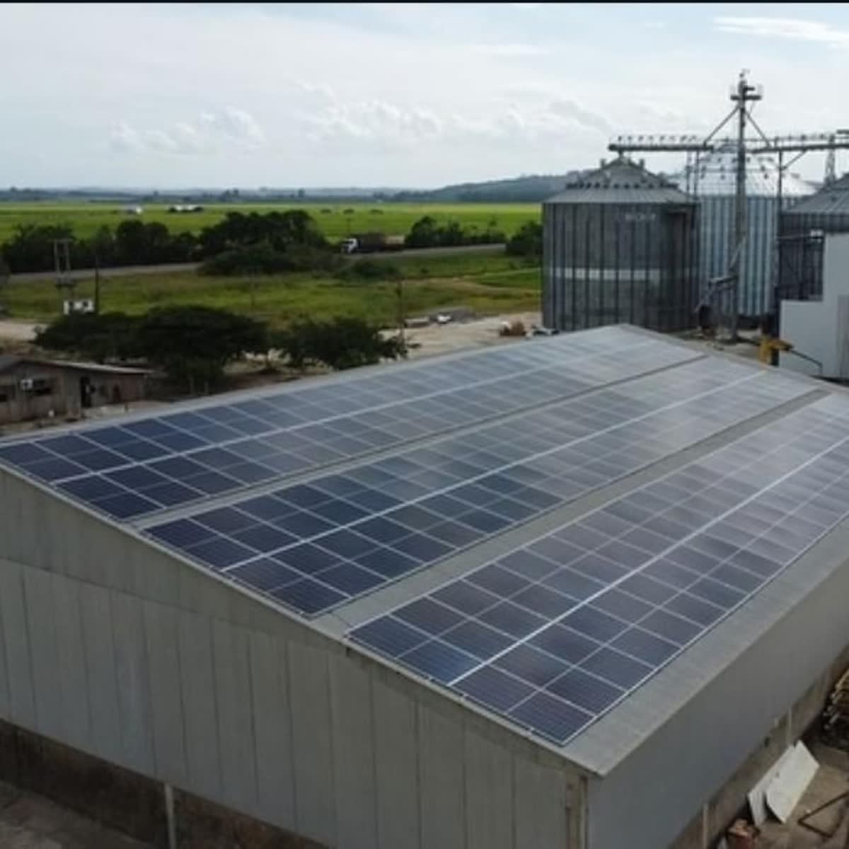 Vista aérea de usina solar em propriedade rural com silos